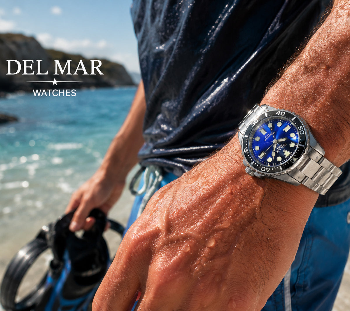 A man at the beach wearing a Del Mar Watches stainless steel dive watch with a blue dial and black bezel. The brand logo 'DEL MAR WATCHES' is displayed in the top left corner.