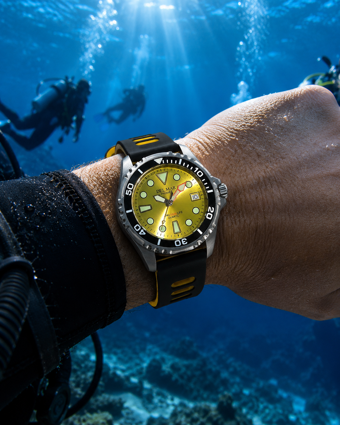 A wristwatch with a bright yellow dial and black strap with yellow accents, worn on a diver's 500 M Pro wrist underwater with other divers and sunbeams in the blue water background.